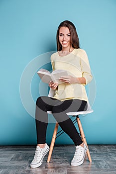 Beautiful girl reading book and sitting on chair