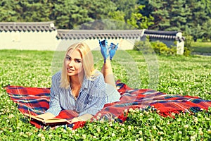 Beautiful girl reading book in the summer park