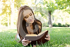 Beautiful girl reading book in the summer park. Young woman with book, summer outdoor