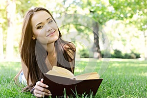 Beautiful girl reading book in the summer park. Young woman with book, summer outdoor