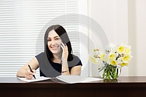 Beautiful girl at the reception desk answering the call in dental office