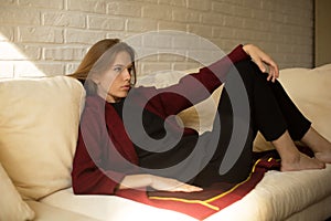 Beautiful girl in a red coat having a rest on the couch