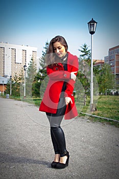 Beautiful girl in a red coat on a park alley