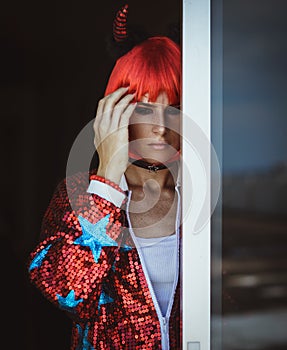 Beautiful girl in a red devil costume holding his hand over his head. Halloween. Headache.