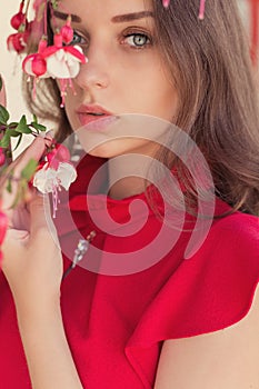 Beautiful girl in a red dress with a gentle look standing near colors