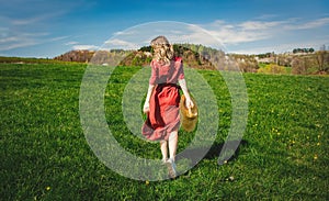 Beautiful girl in red dress and hat have a carefree time on meadow