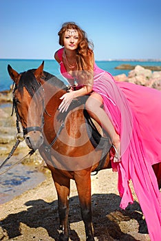 The beautiful girl in red dress sits on horse