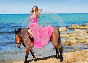 The beautiful girl in red dress sits on horse