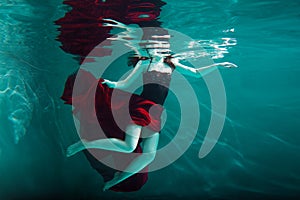 Beautiful girl in a red dress swims under water. amazing Underwater