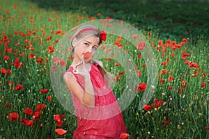 Beautiful girl in red dress walks at poppy field