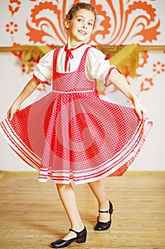 Beautiful girl in red folk costume dances near