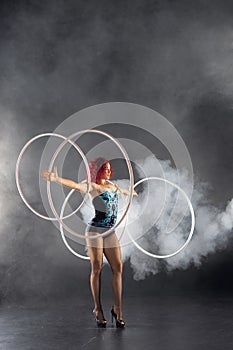 Beautiful girl with red hair circus artist spinning hoops on hands