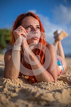 Beautiful girl with red hair posing on the beach. Sunset.