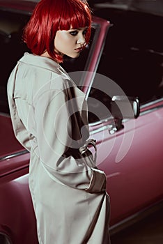 beautiful girl in red wig and stylish trench coat looking away