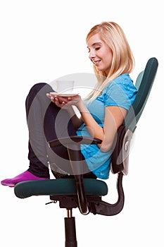 Beautiful girl relaxing in chair holds a cup of tea or coffee.