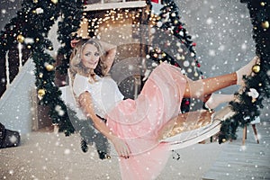 Beautiful girl relaxing on Christmas swing.Christmas tree.