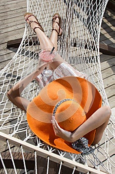 Beautiful girl relaxing on a hammock with a coctail