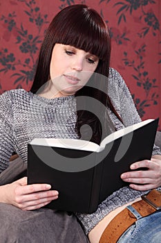 Beautiful girl relaxing at home reading a book
