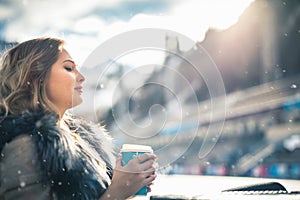 Beautiful girl resting and drinking coffee after ice skating
