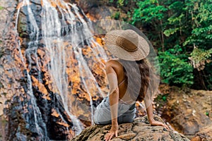 A beautiful girl is resting in the jungle near a waterfall. Na Muang Waterfall at Samui