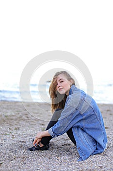 Beautiful girl resting, sitting by sea and posing on camera on b