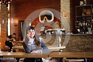 beautiful girl resting and talking on the phone in a cafe ski resort