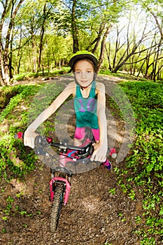 Beautiful girl riding her bike on the forest trail