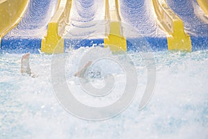 Beautiful girl riding a water slide. happy woman going down on the rubber ring by the orange slide in the aqua park