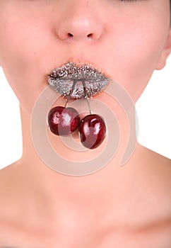 Beautiful girl's lower part of face with two red cherries in mouth