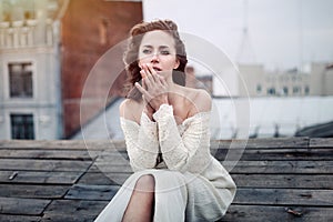 Beautiful girl sad sitting on the roof. Lonely woman in depressive mood on the roof.