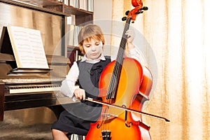 Beautiful girl in school uniform plays on cello