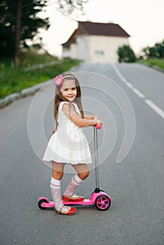 Beautiful girl with scooter on the road