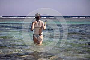 Beautiful girl on the seashore. Clear and clean water. Sunny day.