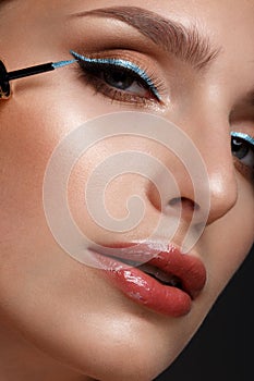 Beautiful girl with sexy lips and classic makeup with cosmetic blue eyeliner in hand. Beauty face.