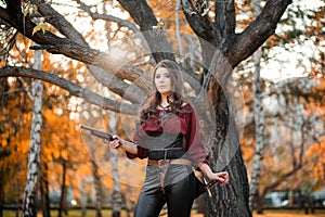 A beautiful girl in a shirt corset and tight trousers with a saber and a pistol in her hands