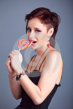 Beautiful girl with short hair licking a lollipop