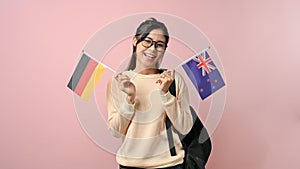 Beautiful girl showing Germany and New Zealand flag on pink isolated background