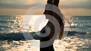 Beautiful girl side view on the beach portrait looks into the distance and smiles. Long hair blows in the wind. Sunny