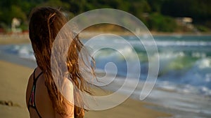 Beautiful girl side view on the beach portrait looks into the distance and smiles. Long hair blows in the wind. Sunny