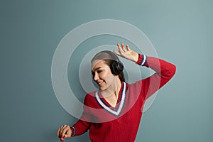 Beautiful girl singing favorite song, listening to music in wireless headphones, smiling and dancing