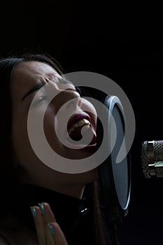 Beautiful girl singing In Recording Studio with microphone