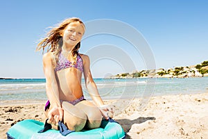 Beautiful girl sits on the beach with rubber ring