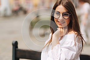 Beautiful girl sits on benth in centre of city. She relaxes and waits for her husband