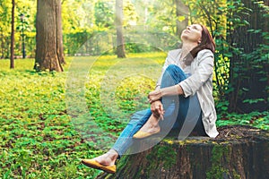 Carino una donna è un contento da pittoresco natura. campeggio Riposo bella ragazza si siede sul il grande vecchio tronco d'albero foresta 