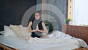 Beautiful girl is sitting in bed, meditating. Yoga