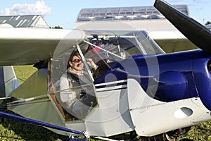 beautiful girl sitting in the cockpit of a small two-seater plan