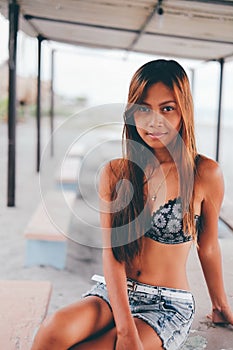 Beautiful girl sitting on the concrete table beneath the sunshade