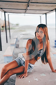 Beautiful girl sitting on the concrete table beneath the sunshade