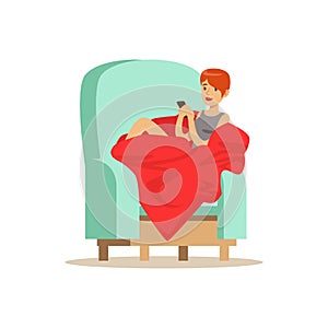 Beautiful girl sitting on a light blue armchair wrapped in a red blanket