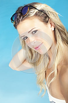 Beautiful blonde hair girl sitting near the pool in swimsuit. Summer concept